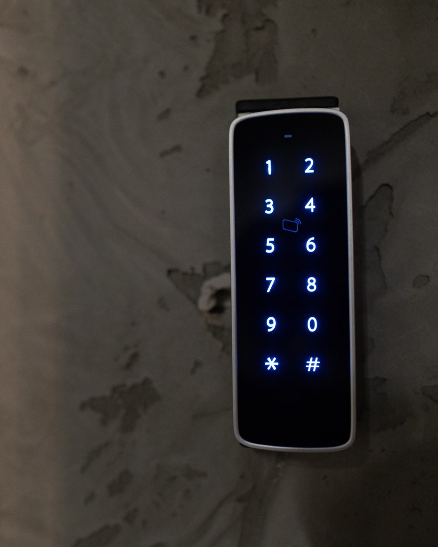 Illuminated keypad access control reader mounted beside a doorway