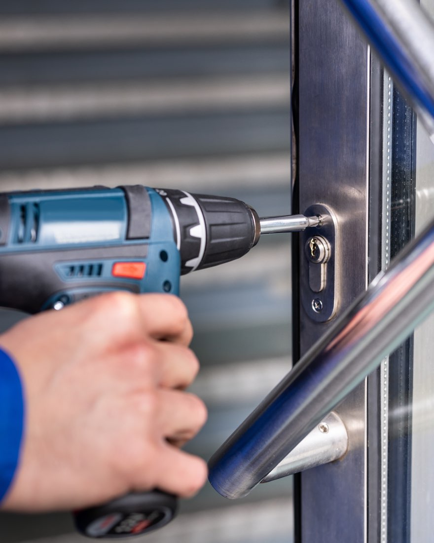 Technician installing a lock cylinder in a commercial glass door